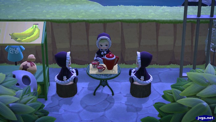 Three dolls sit around a tea set.